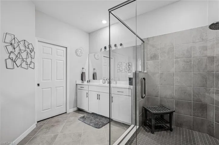 Bathroom with vanity, a shower stall, tile patterned floors, and recessed lighting