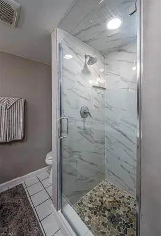 Bathroom with toilet, tile patterned floors, and an enclosed shower