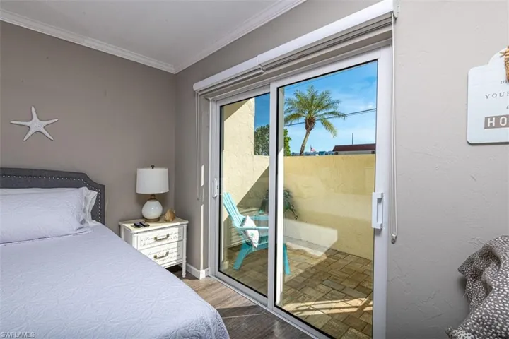 Bedroom with light hardwood / wood-style floors, crown molding, and access to outside