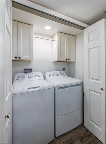 Laundry room with dark hardwood / wood-style floors, cabinets, and washing machine and clothes dryer