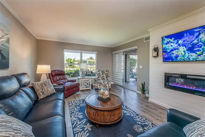 Living room featuring a large fireplace, hardwood / wood-style flooring, and crown molding