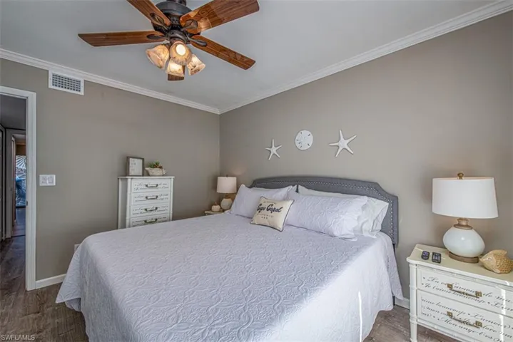 Bedroom featuring ceiling fan, dark wood-type flooring, and ornamental molding