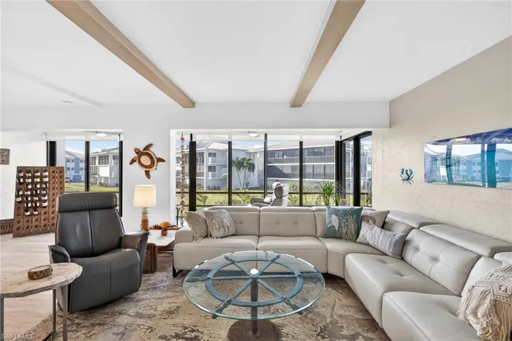 Living area with plenty of natural light, beamed ceiling, and a textured wall