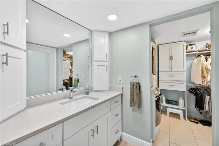 Full bathroom featuring a walk in closet, vanity, stacked washer and clothes dryer, and light tile patterned floors