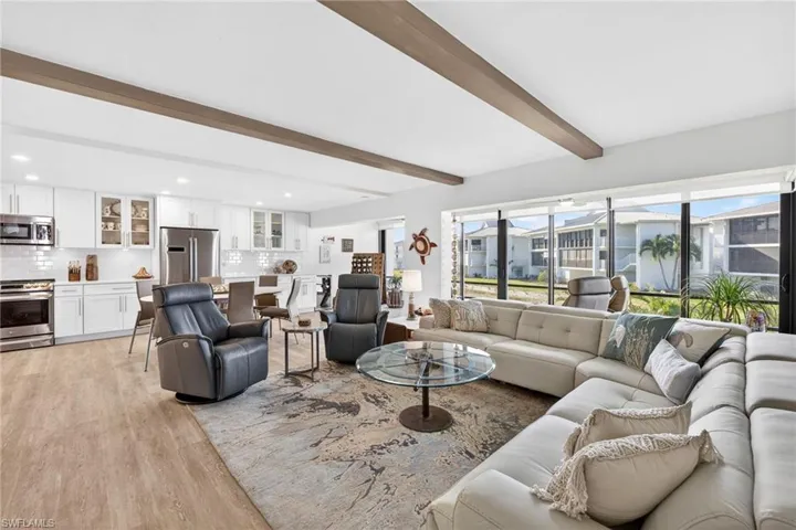 Living room with beam ceiling and light wood-type flooring
