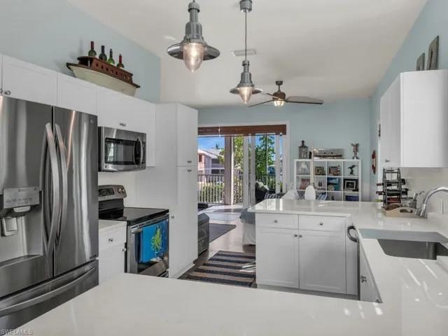 Kitchen featuring stainless steel appliances, ceiling fan, white cabinetry, and sink