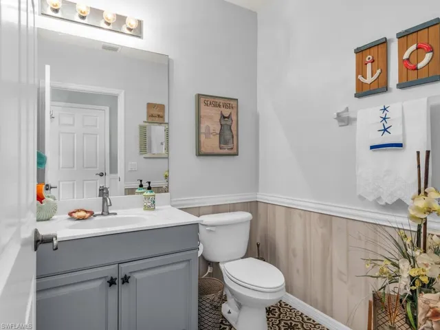 Bathroom featuring vanity, toilet, and wooden walls