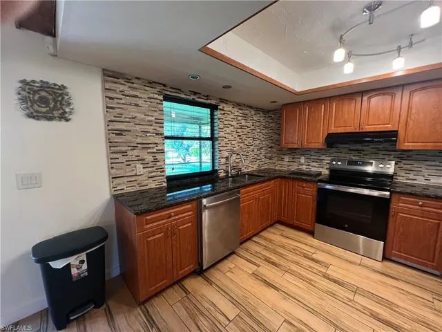 Kitchen with stainless steel appliances, brown cabinets, and backsplash