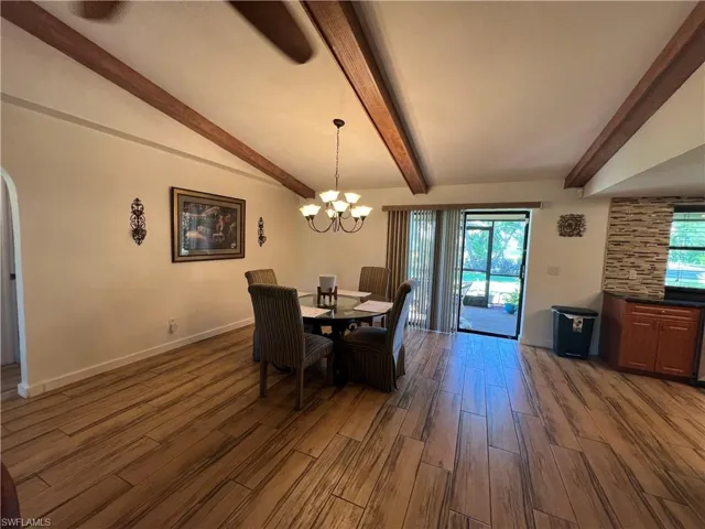 Dining area featuring a chandelier, dark wood-style floors, and beamed ceiling