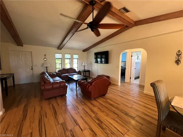Living area with arched walkways, light wood-type flooring, and a ceiling fan