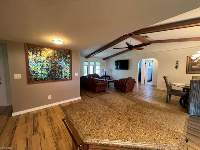 Living room featuring wood finished floors, ceiling fan, and arched walkways