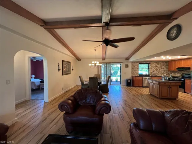 Living area featuring a ceiling fan, a chandelier, light wood-style floors, and arched walkways