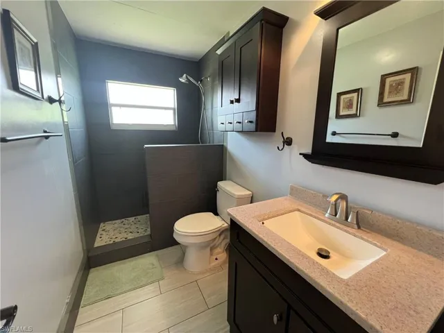 Full bathroom featuring walk in shower, vanity, and tile patterned flooring