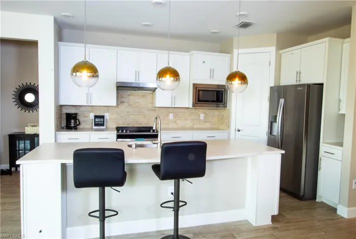 Well-lighted open kitchen with island and quartz countertops