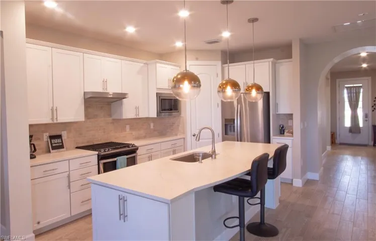 Well-lighted open kitchen with island and quartz countertops