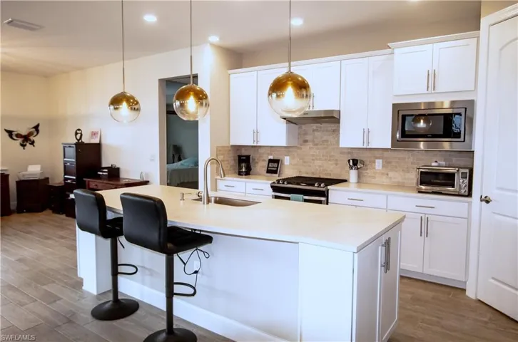 Well-lighted open kitchen with island and quartz countertops