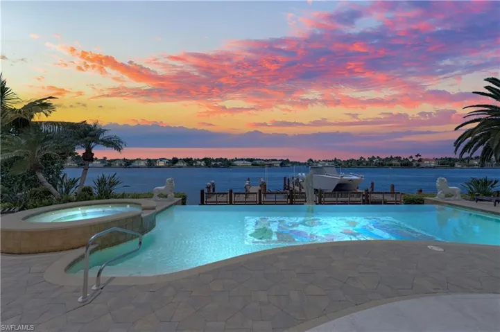 Pool at dusk featuring an in ground hot tub and a water view