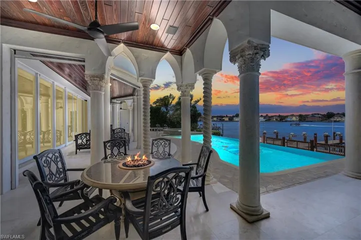 Patio terrace at dusk with an outdoor fire pit, a water view, and ceiling fan