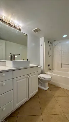 Full bathroom with toilet, vanity, tile patterned floors, and shower / washtub combination