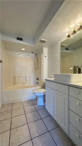 Full bathroom with tile patterned flooring, vanity, toilet, and tiled shower / bath combo