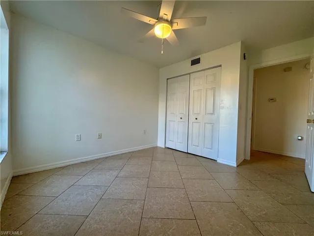 Unfurnished bedroom featuring ceiling fan, light tile patterned floors, and a closet