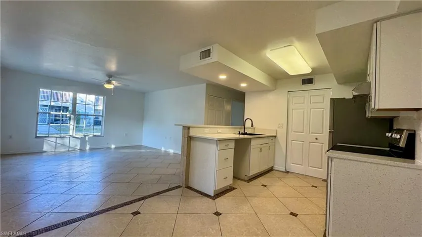 Kitchen featuring stove, white cabinets, sink, ceiling fan, and kitchen peninsula