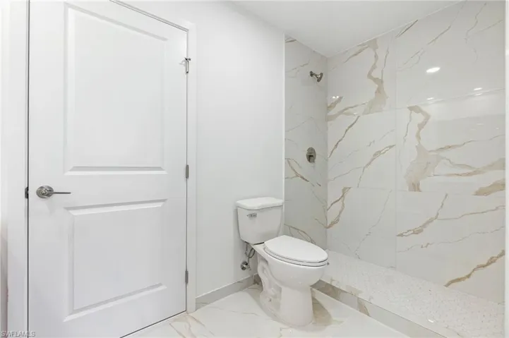 Full bath with toilet, a marble finish shower, and marble finish floor
