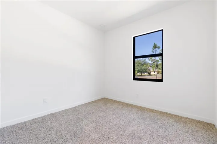 Carpeted spare room featuring baseboards