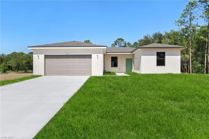 View of front of house with an attached garage, concrete driveway, stucco siding, and a front yard