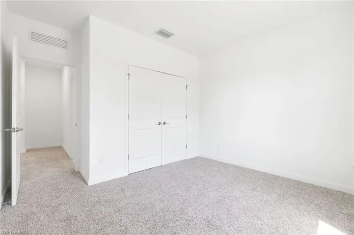 Unfurnished bedroom featuring light colored carpet, a closet, visible vents, and baseboards