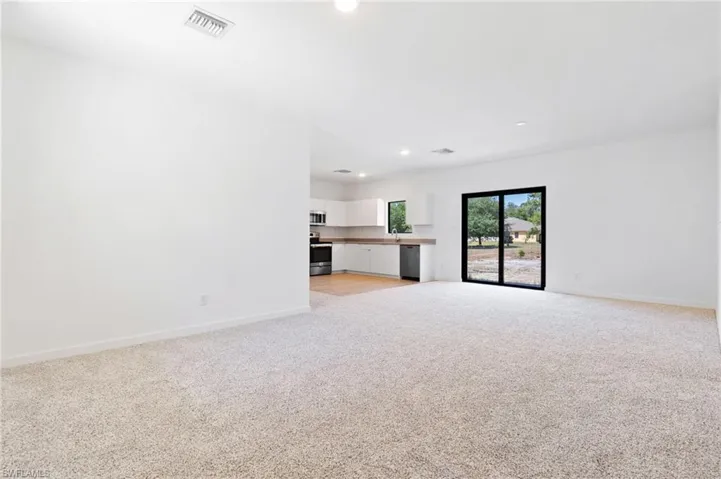 Unfurnished living room with light colored carpet, visible vents, baseboards, and recessed lighting