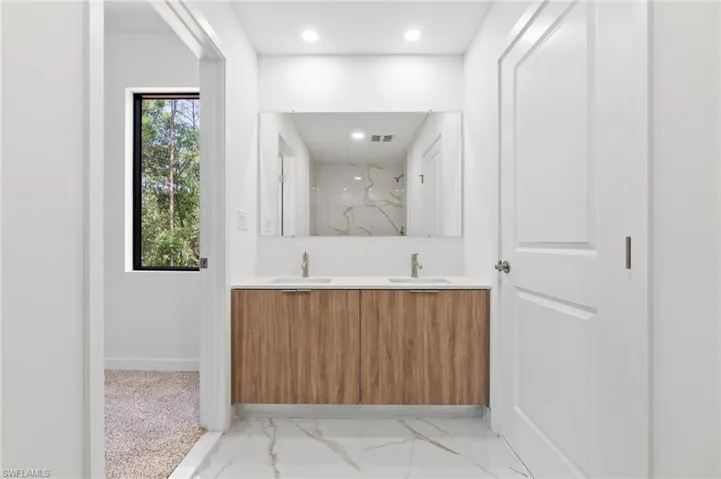 Full bathroom featuring double vanity, a marble finish shower, a sink, marble finish floor, and recessed lighting