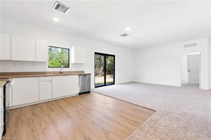 Kitchen with a sink, stainless steel dishwasher, and visible vents