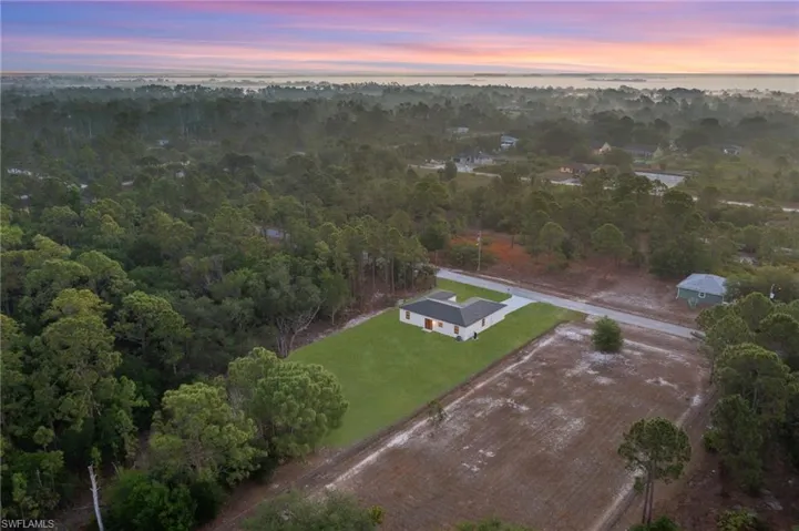 Aerial view at dusk featuring a water view and a forest view