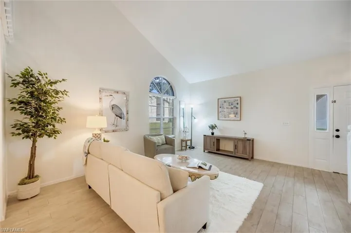 Living area with light wood-type flooring and high vaulted ceiling