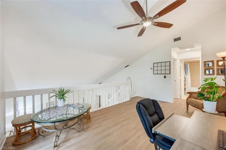 Office space with vaulted ceiling, wood finished floors, and ceiling fan