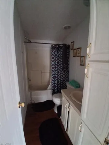 Bathroom with vanity, shower / tub combo, and dark wood-style flooring
