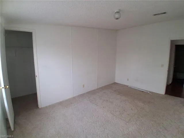 Unfurnished bedroom with light carpet, a textured ceiling, and a spacious closet