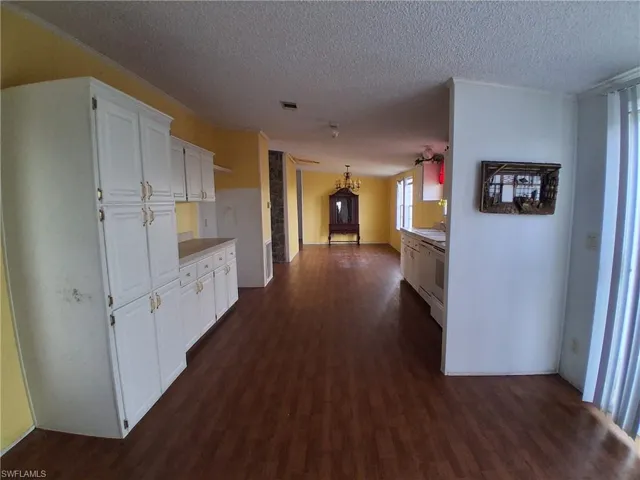 Hall with a chandelier, dark wood-style flooring, and a textured ceiling