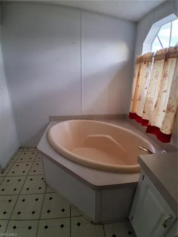 Bathroom with a bath, vanity, a textured ceiling, and light floors