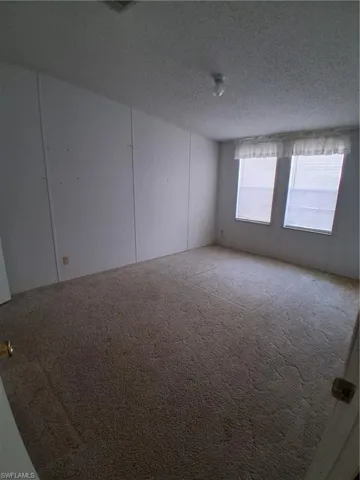 Carpeted empty room featuring a textured ceiling