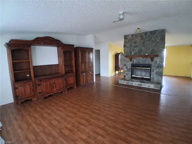 Unfurnished living room featuring a fireplace and dark wood-style flooring