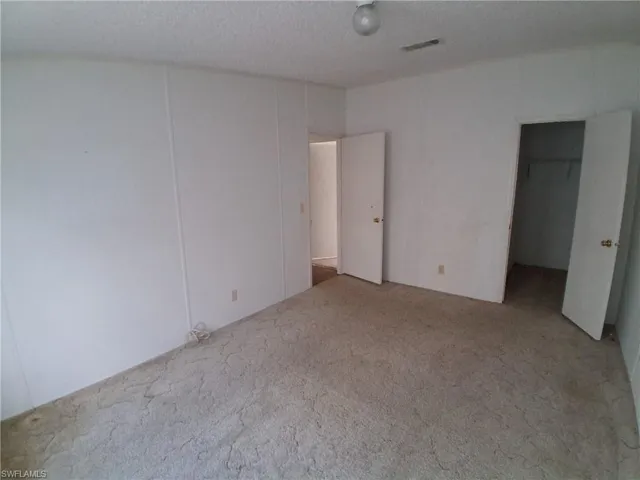 Unfurnished bedroom with carpet flooring, a spacious closet, and a textured ceiling