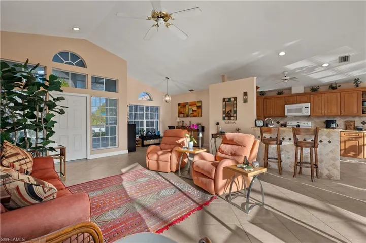 Living room featuring ceiling fan, light tile patterned floors, and vaulted ceiling