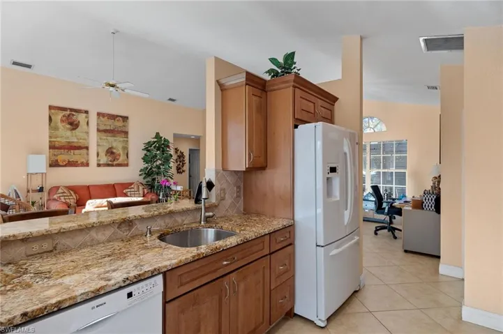 Kitchen featuring ceiling fan, sink, light stone countertops, white appliances, and light tile patterned floors