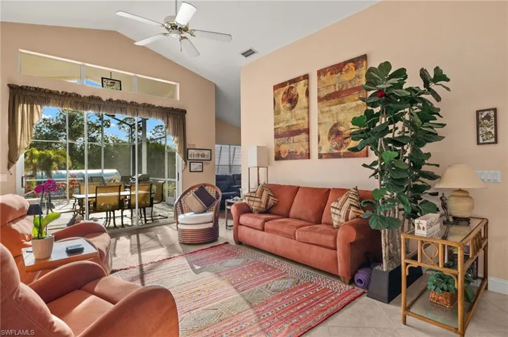 Living room featuring light tile patterned floors, ceiling fan, and lofted ceiling