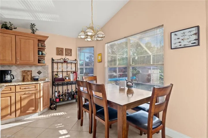 Tiled dining room with vaulted ceiling and an inviting chandelier