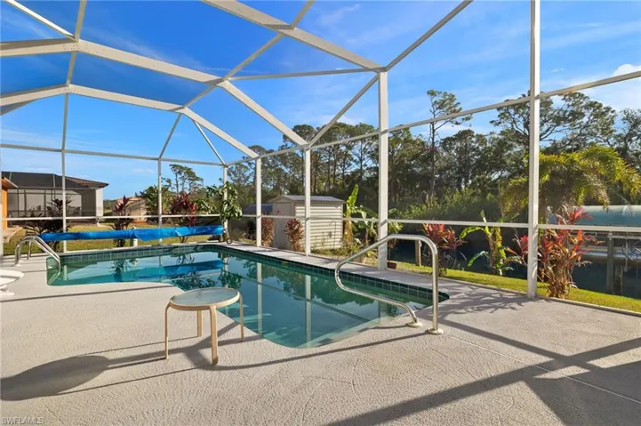 View of swimming pool featuring a lanai, a patio, and a storage unit