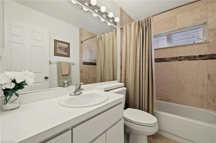 Full bathroom with vanity, shower / bath combination with curtain, and toilet
