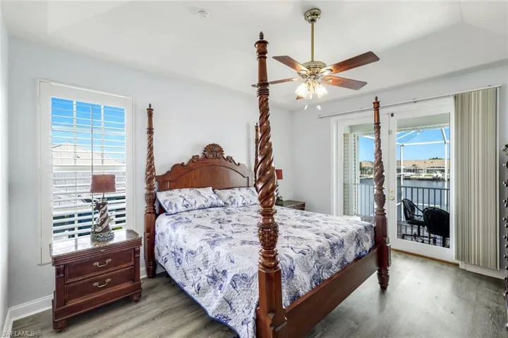 Bedroom with wood finished floors, access to exterior, ceiling fan, and a water view